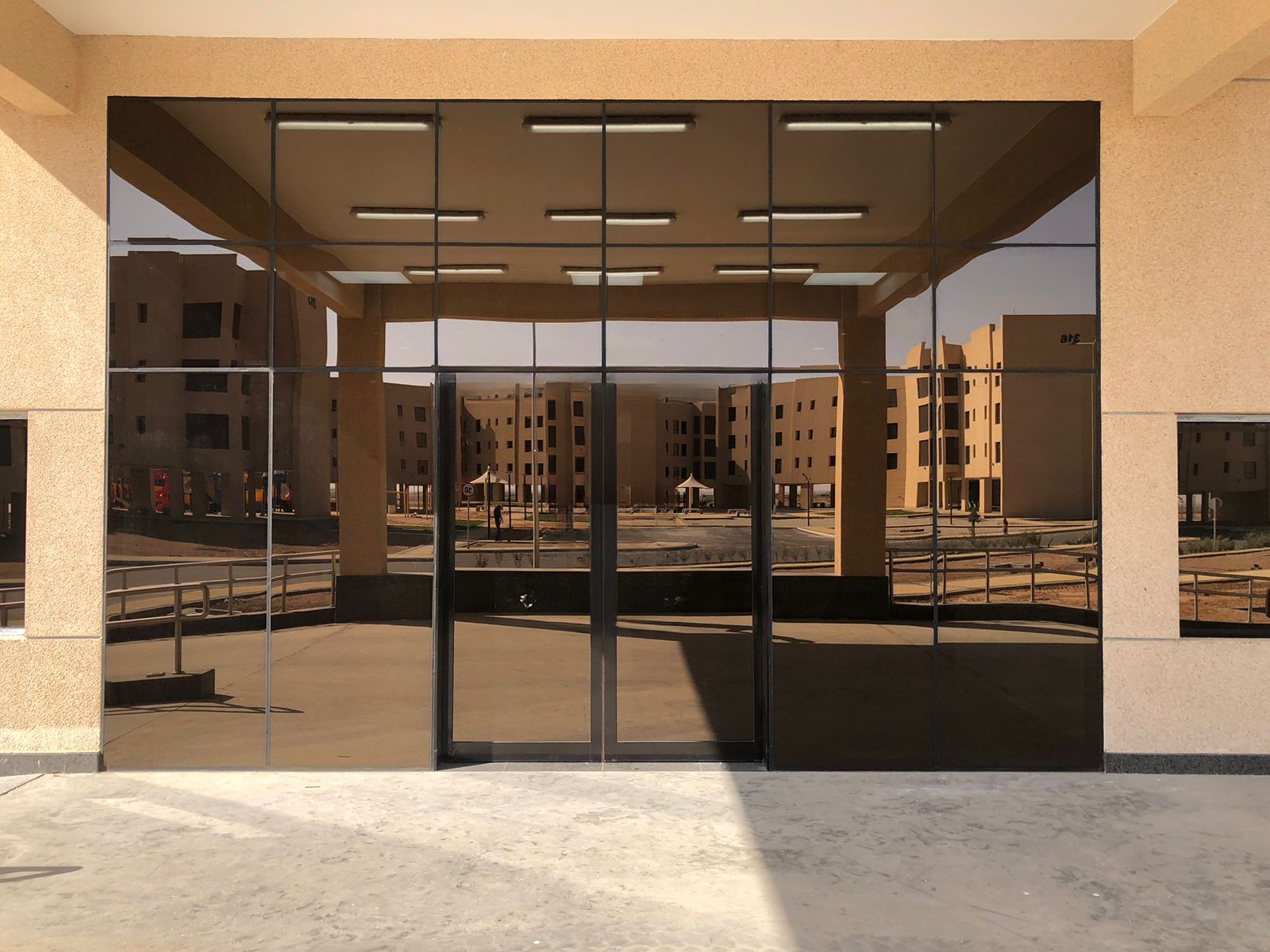 Entrance glazed in dark reflective insulated units, mirroring the buildings across the plaza